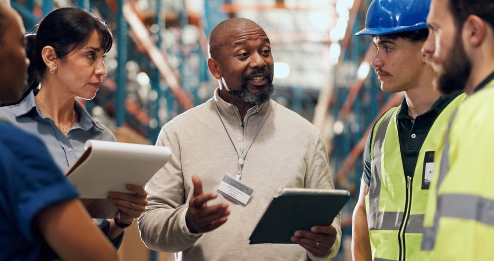 Logistics professionals discussing supply chain solutions in warehouse setting.
