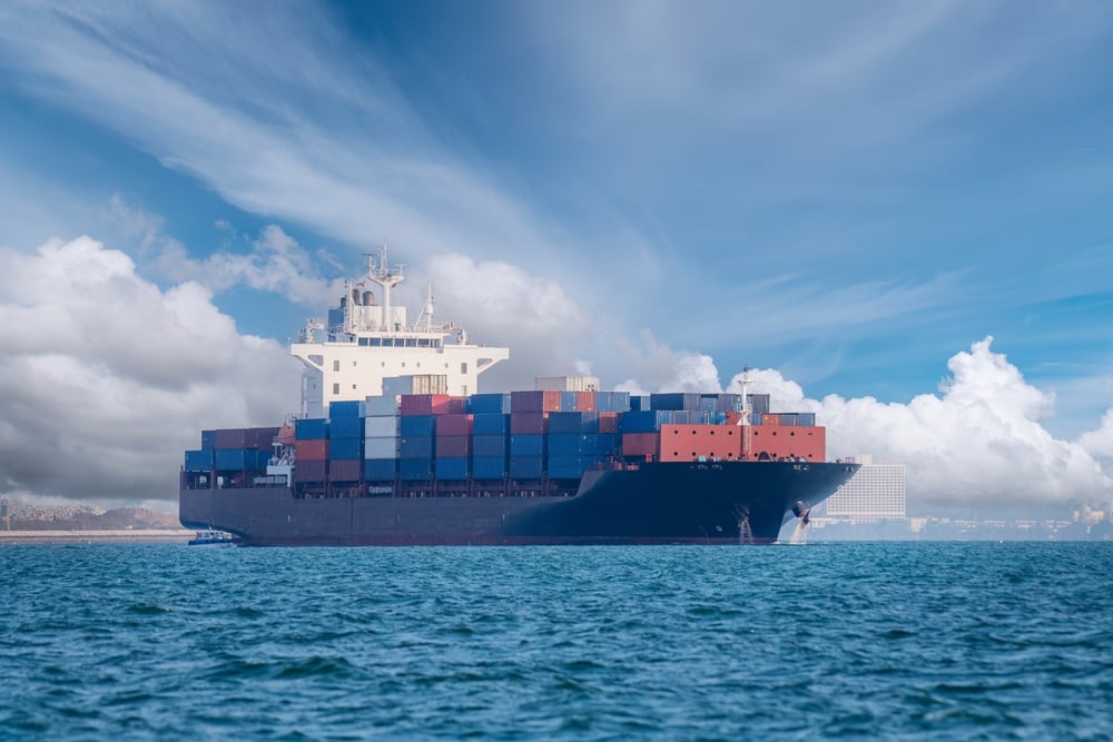 Transportation on open blue sea logistics and container dock cargo yard with crane bridge in shipyard with transport logistic import export with blue sky background.